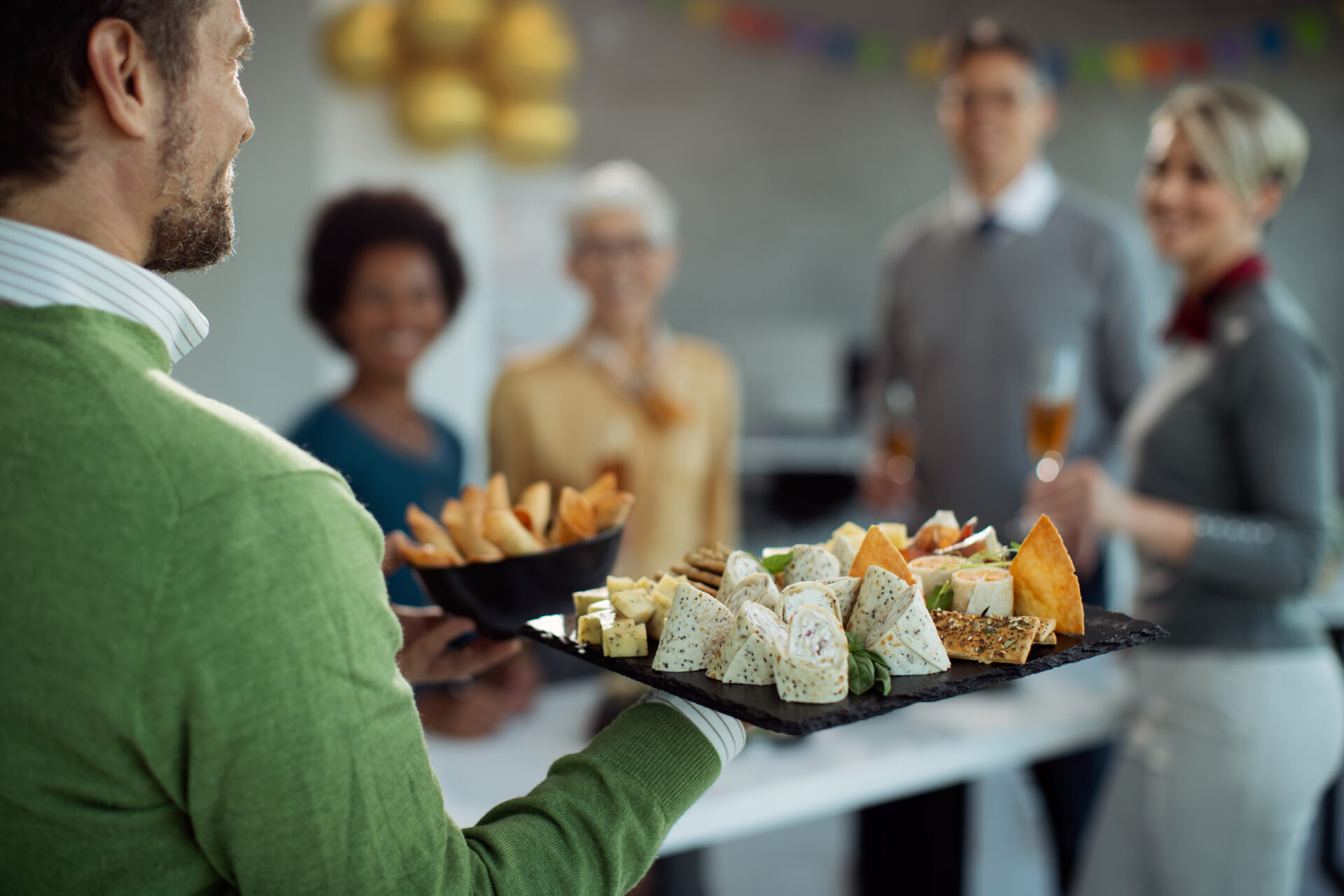 Close-up of entrepreneur serving food to his colleagues while having a party in the office.